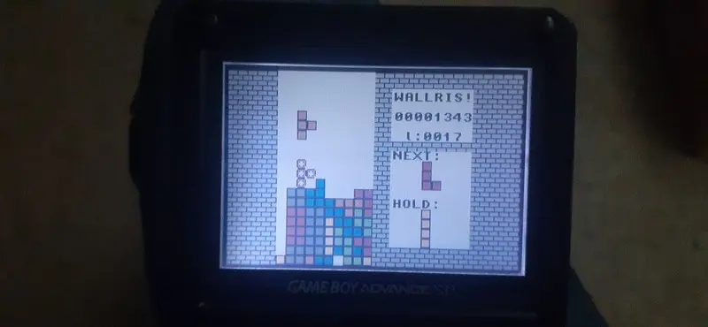 The game running on a Gameboy Advance SP in a dark room.